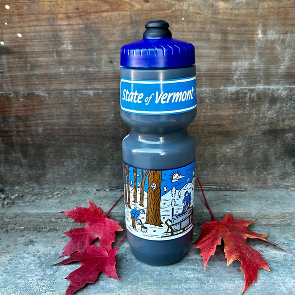 a blue and grey waterbottle sitting on a rough wooden surface
